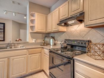 Furnished model kitchen area with black appliance package and tile backsplash